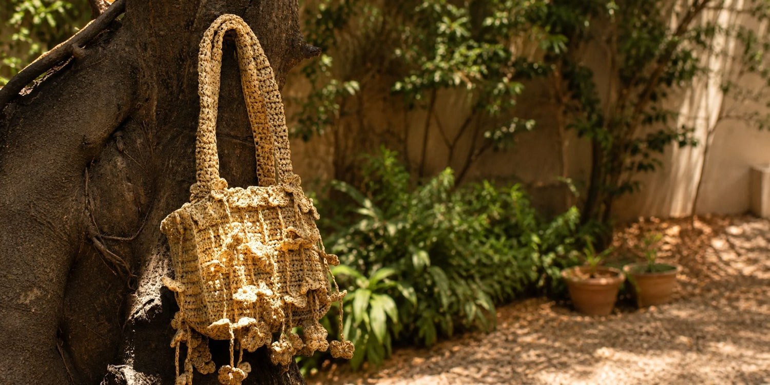 Handcrafted floral raffia shoulder bag hanging on a tree in a sunlit garden setting
