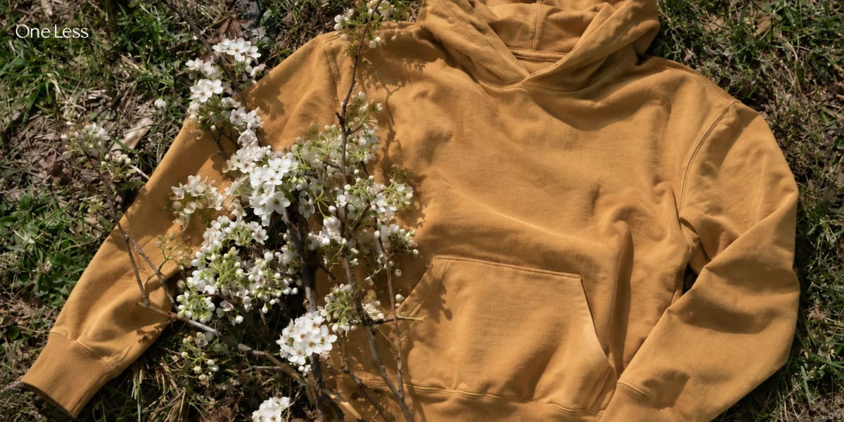 Organic cotton hoodie in mustard yellow displayed on a model, featuring a relaxed fit, long sleeves, and a comfortable kangaroo pocket.